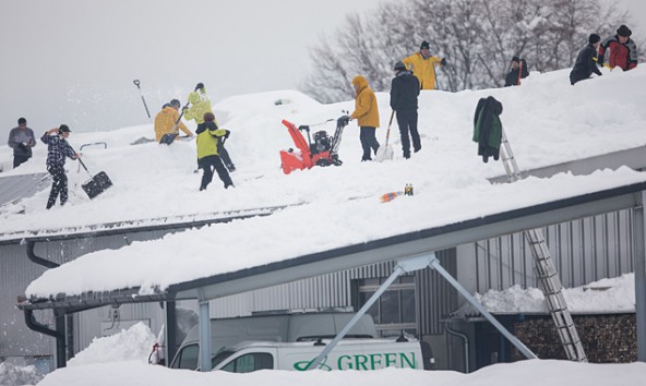 Mitarbeiter und Helfer schaufeln das Dach einer Eletrofirma in Osttirol frei. Der Schnee ist schwer geworden. Foto: Expa/Groder