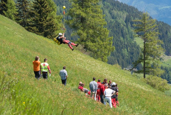 Aus der Luft schwebt Rettung ein. Der Gleitschirmpilot wird mittels Seil geborgen. Foto: Brunner Images